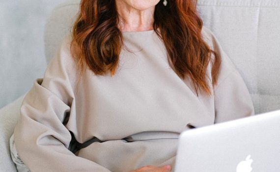 charming elderly woman using laptop on sofa